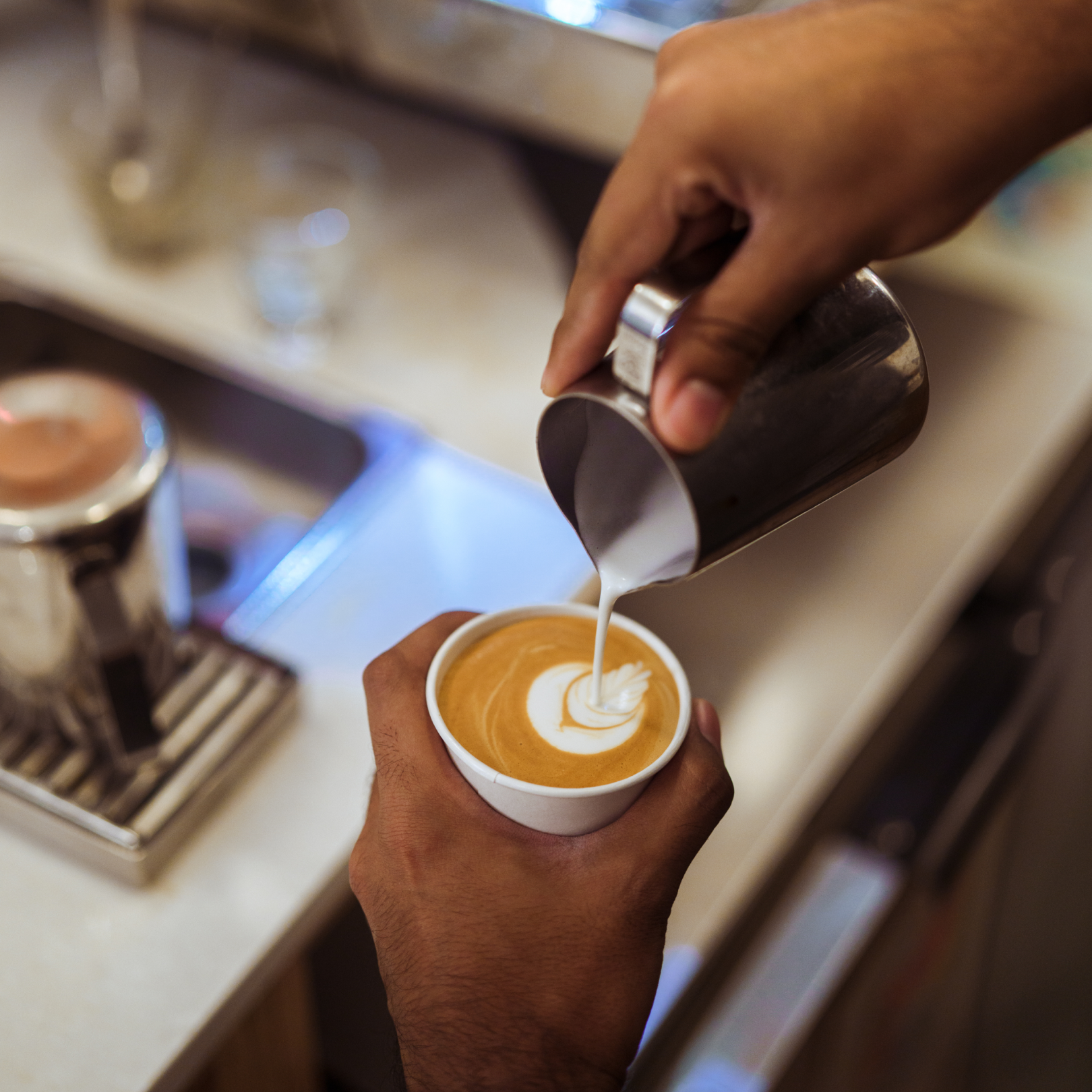 Person pouring milk into a cup of coffee from Café Grumpy at Rockefeller Center