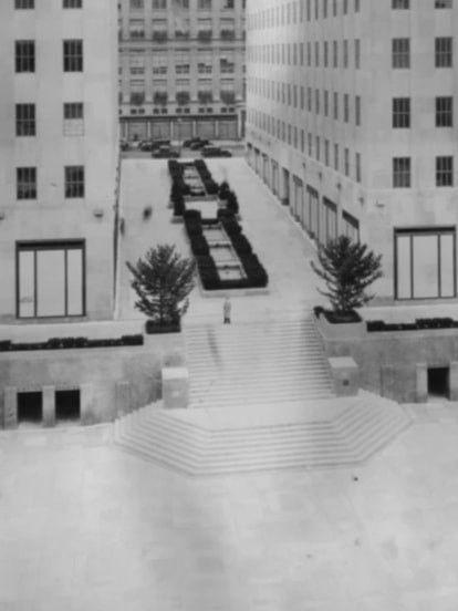 Black-and-white photo of Rockefeller Center’s sunken plaza in 1934 before the skating rink was built, showing stairs and open space between buildings.
