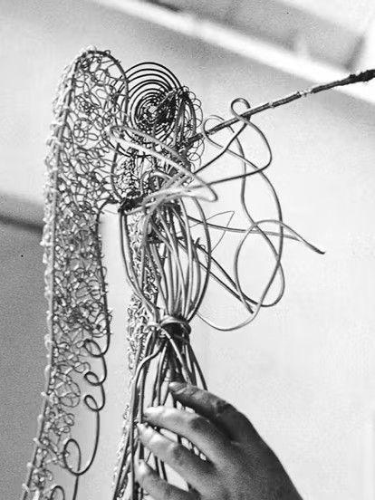 Black-and-white photo of sculptor Valerie Clarebout shaping a wire angel figure, part of the Rockefeller Center holiday display introduced in 1969.