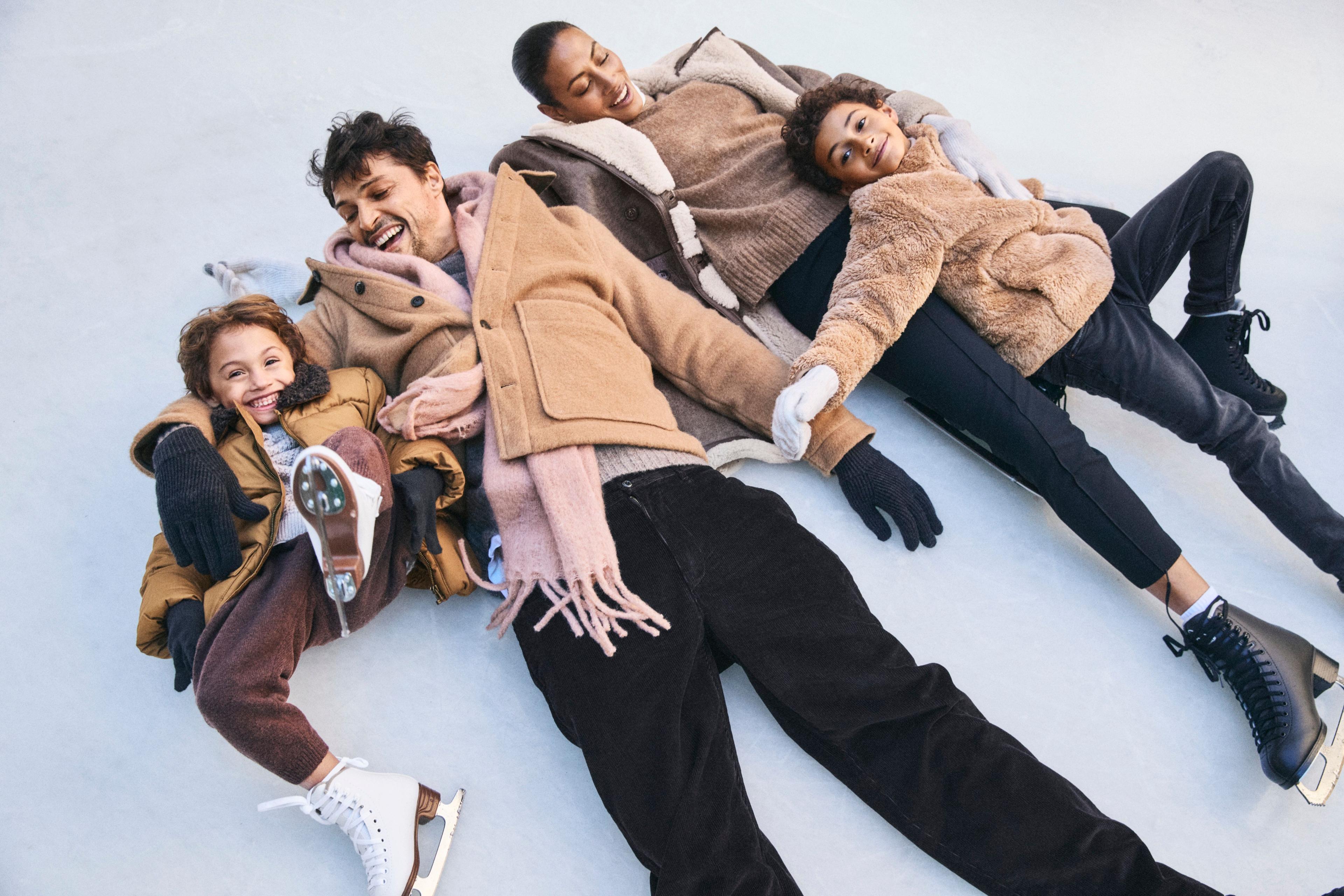 a family smiling laying down on the ice at rockefeller center