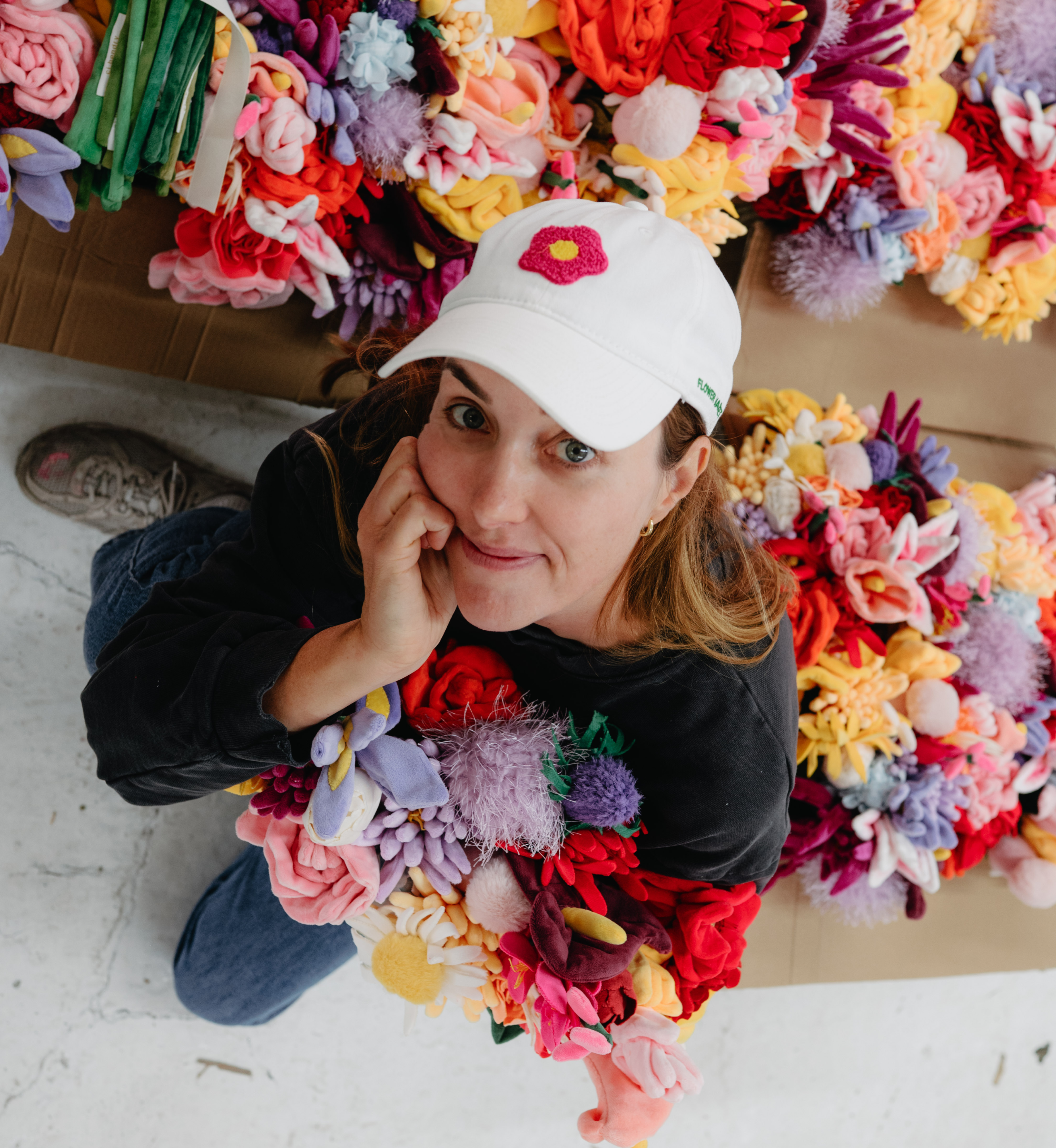 Artist Cj Hendry posing with her plush flower designs ahead of her 'Flower Market' activation at Rockefeller Center