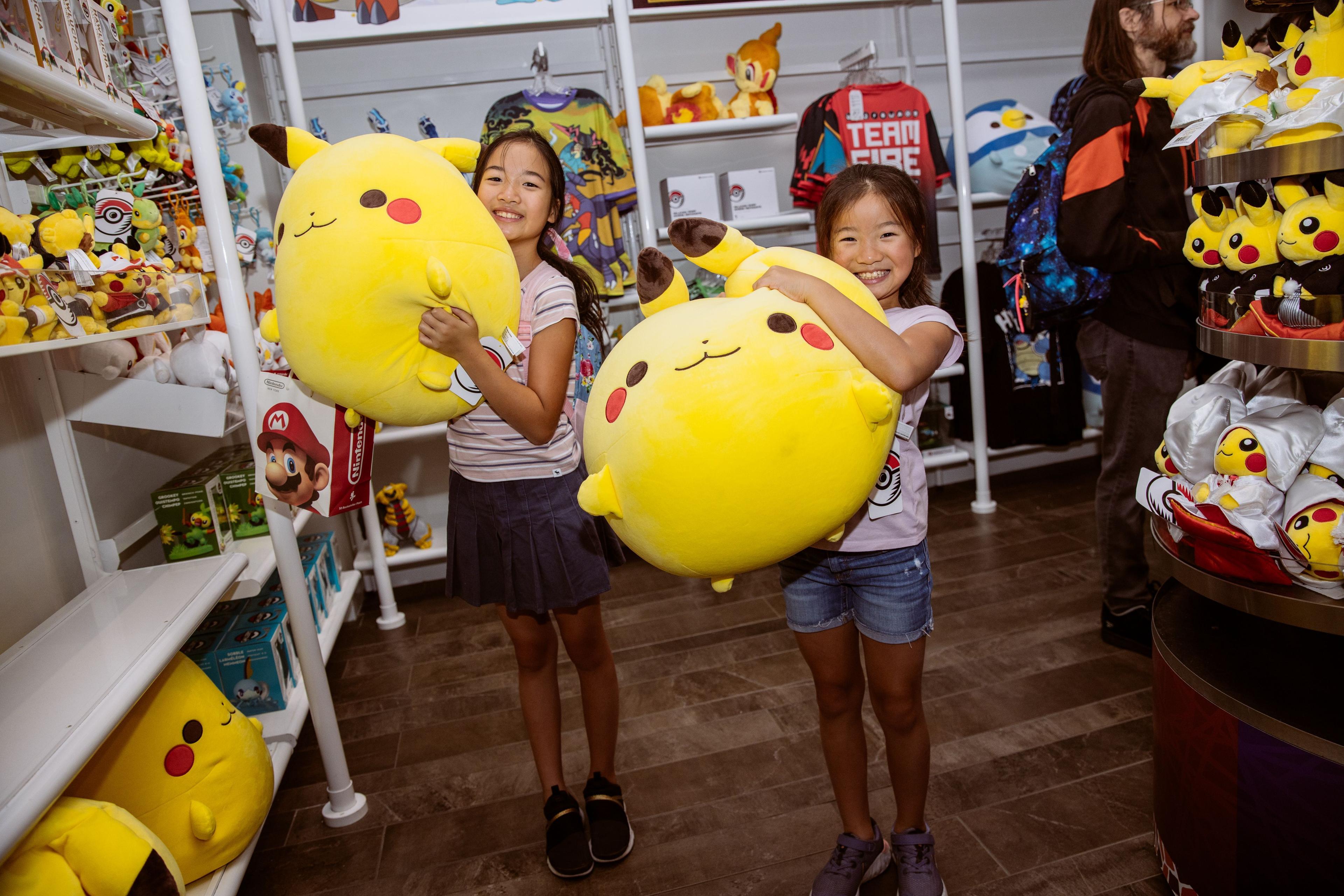 Two girls holding Pikachu stuffed animals