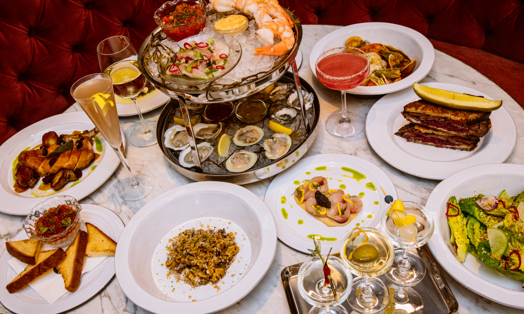 Plates of food and various cocktails on a table at Smith & Mills at Rockefeller Center