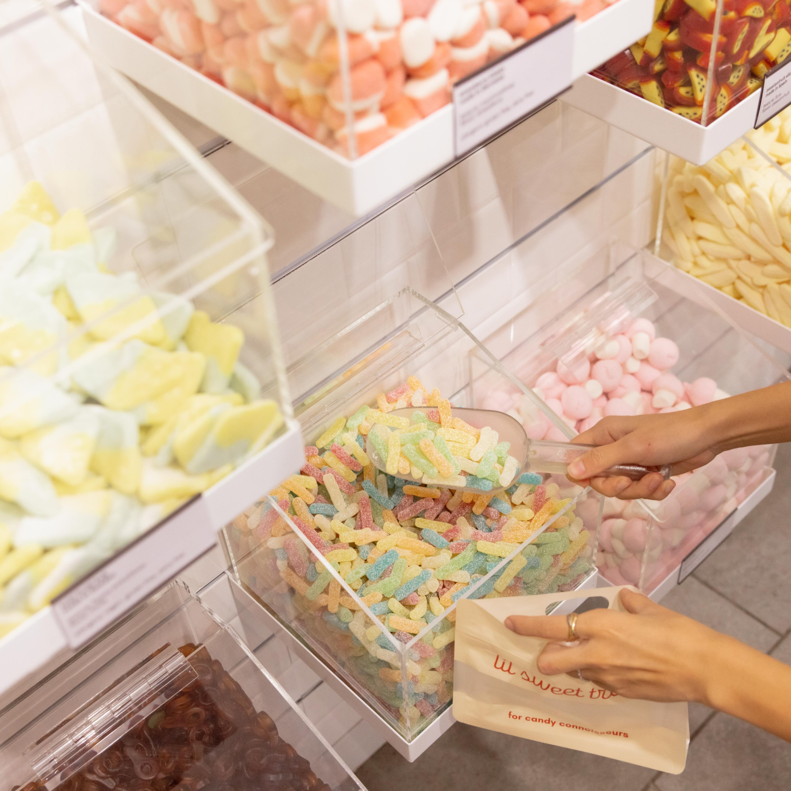 Hand scooping candy into a bag at lil sweet treat at Rockefeller Center