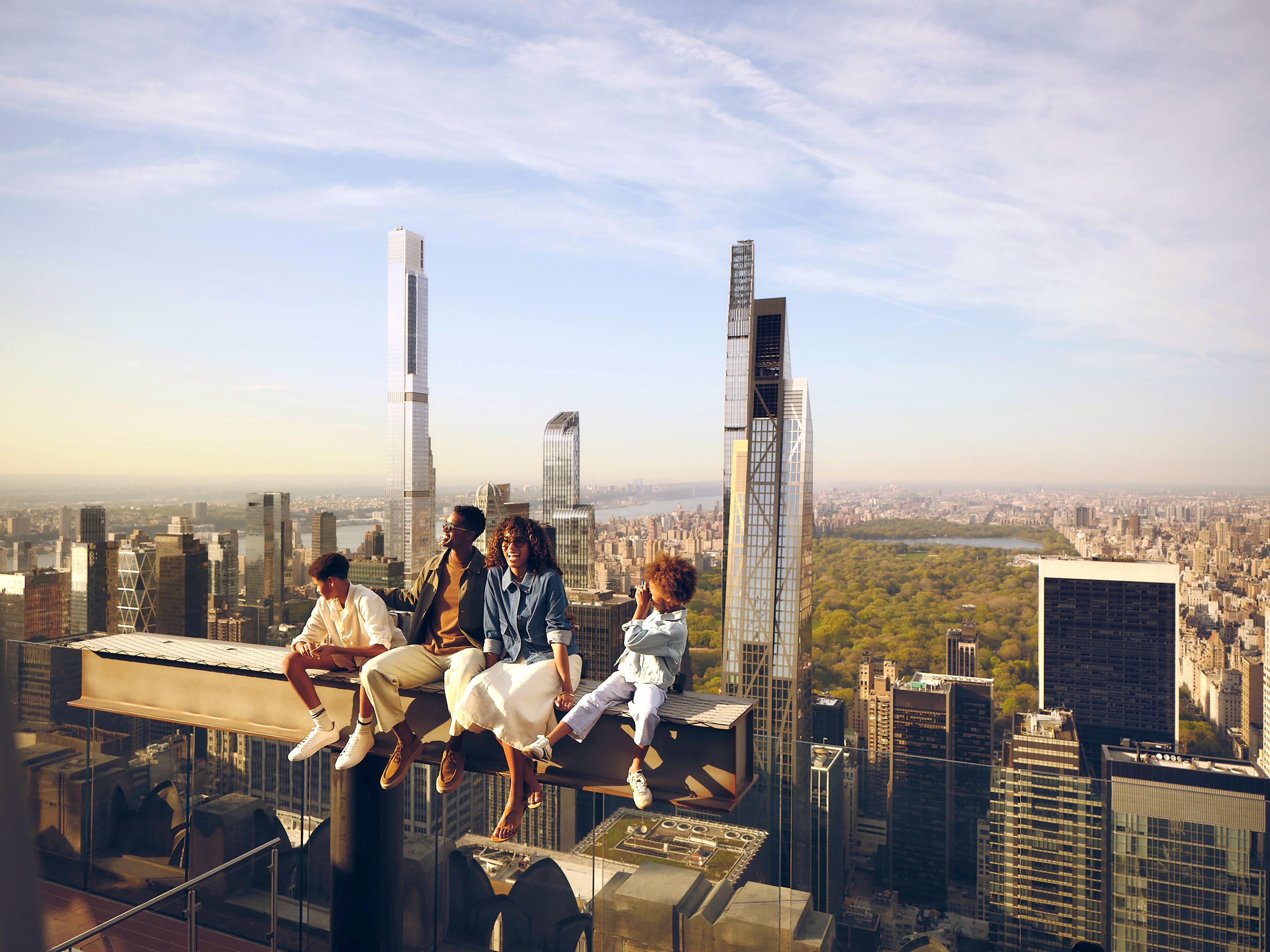 family sitting on The Beam at Top of the Rock
