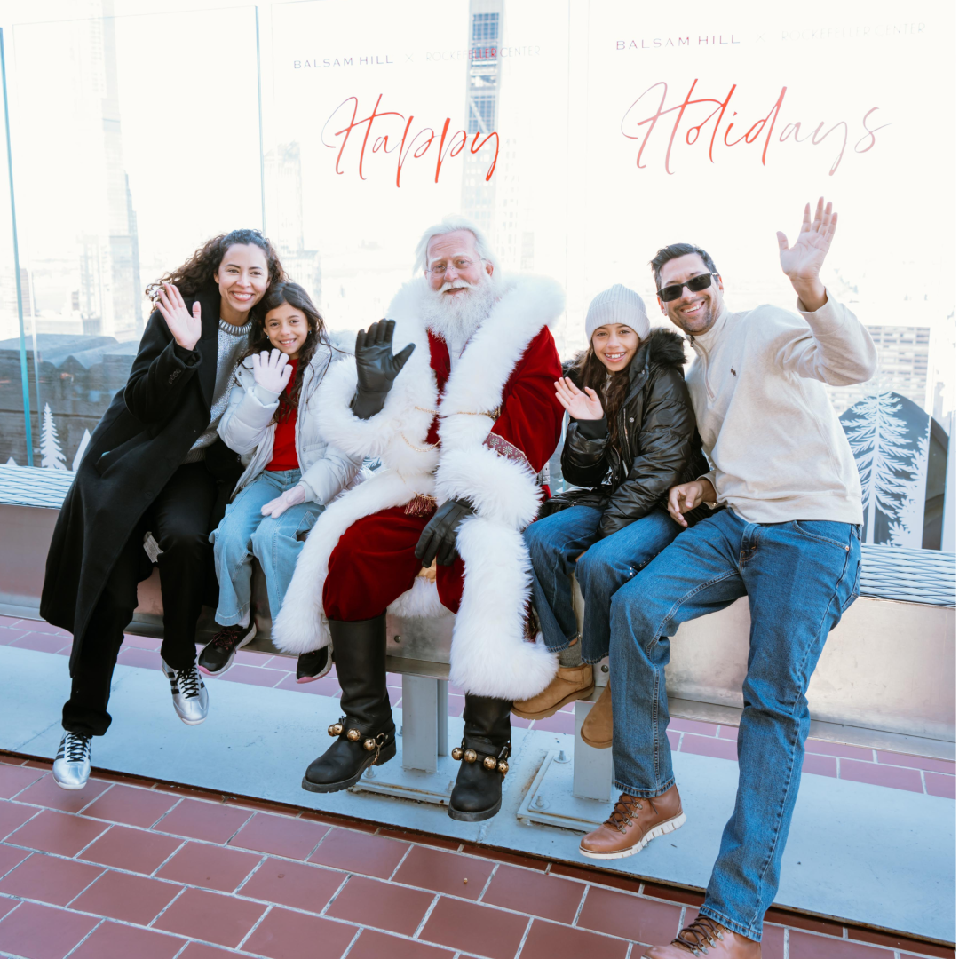 A family of four taking a photo with Santa Claus on The Beam at Top of the Rock