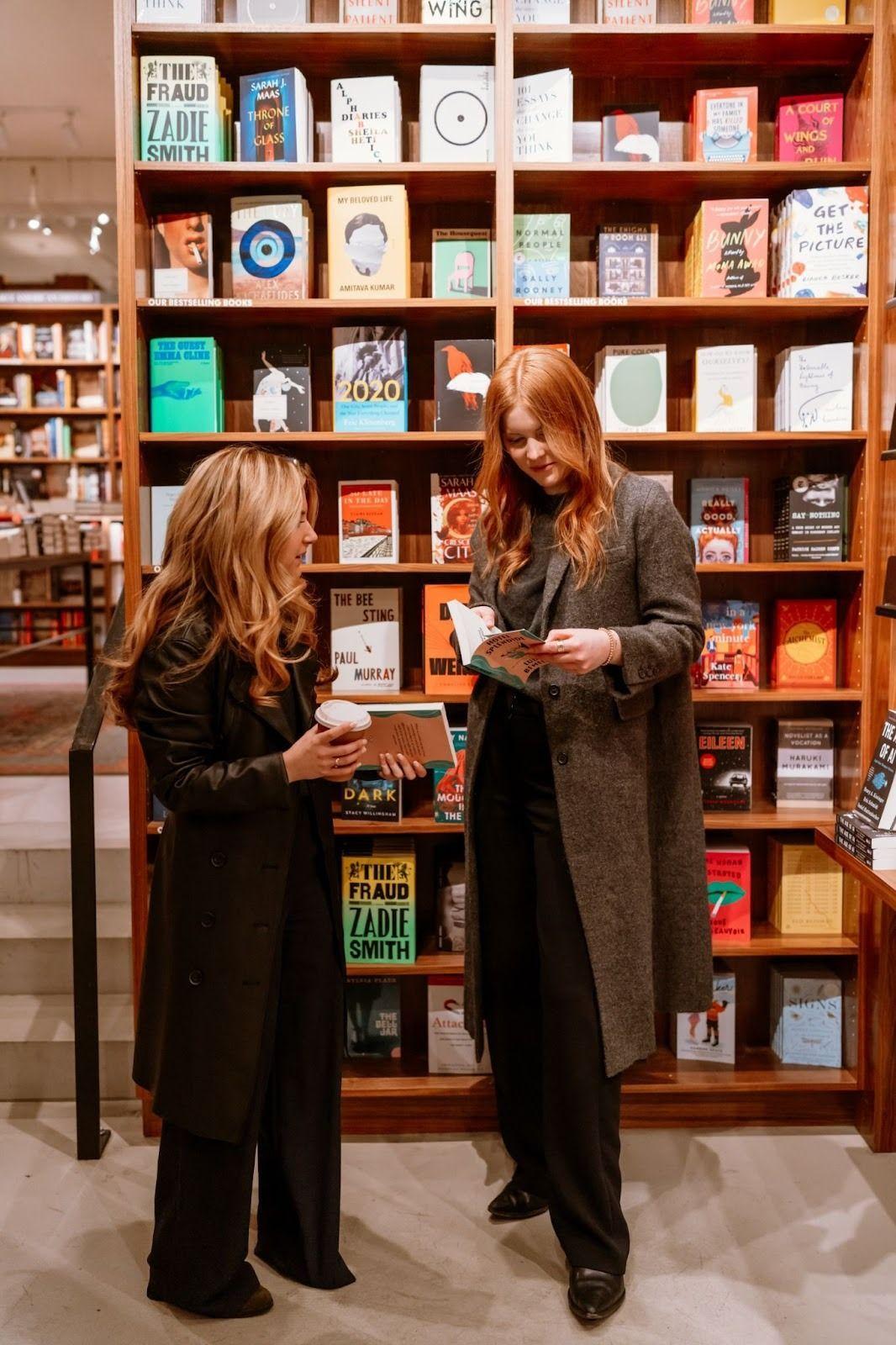 two women standing in a bookstore holding books