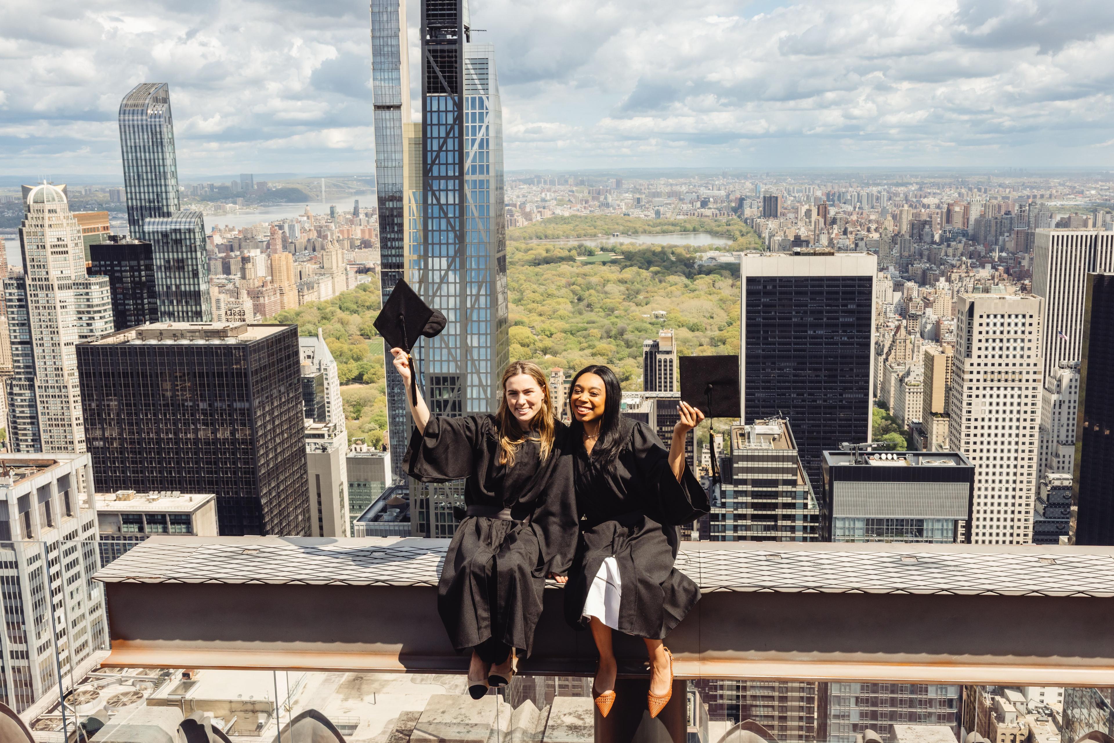 two graduates on the beam at top of the rock