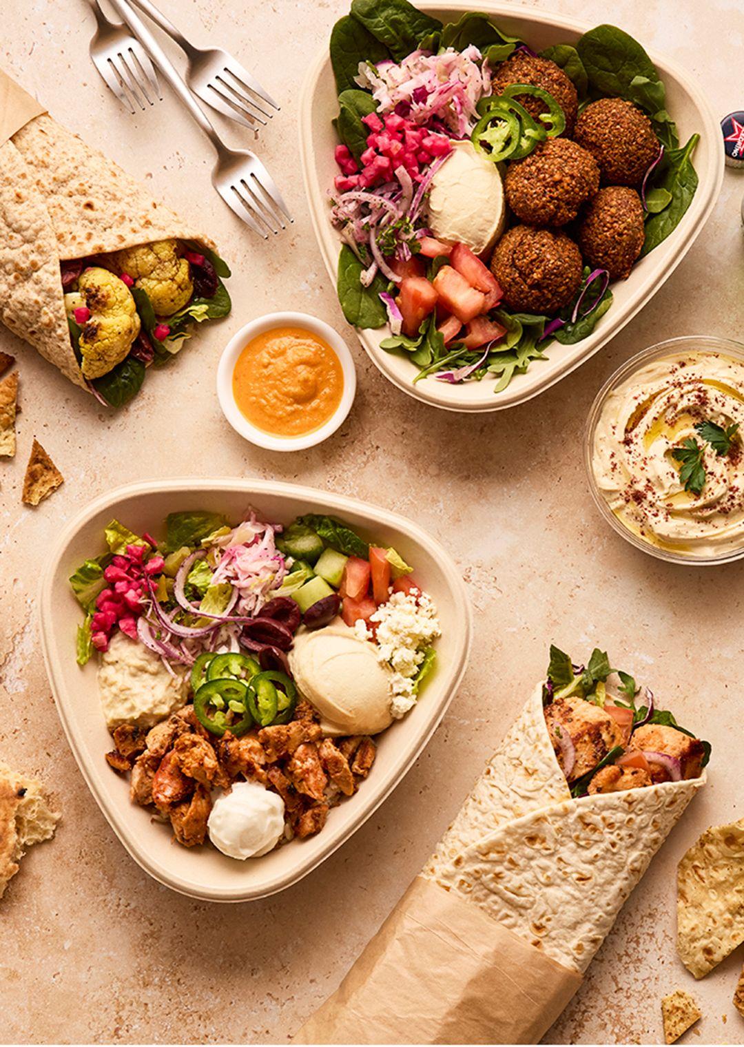 Mediterranean bowls and wraps on a table with pita bread
