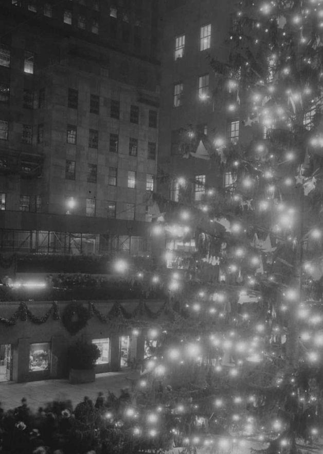 Black-and-white photo of the Rockefeller Center Christmas Tree illuminated at night during the early 1930s, with lights glowing across the branches.