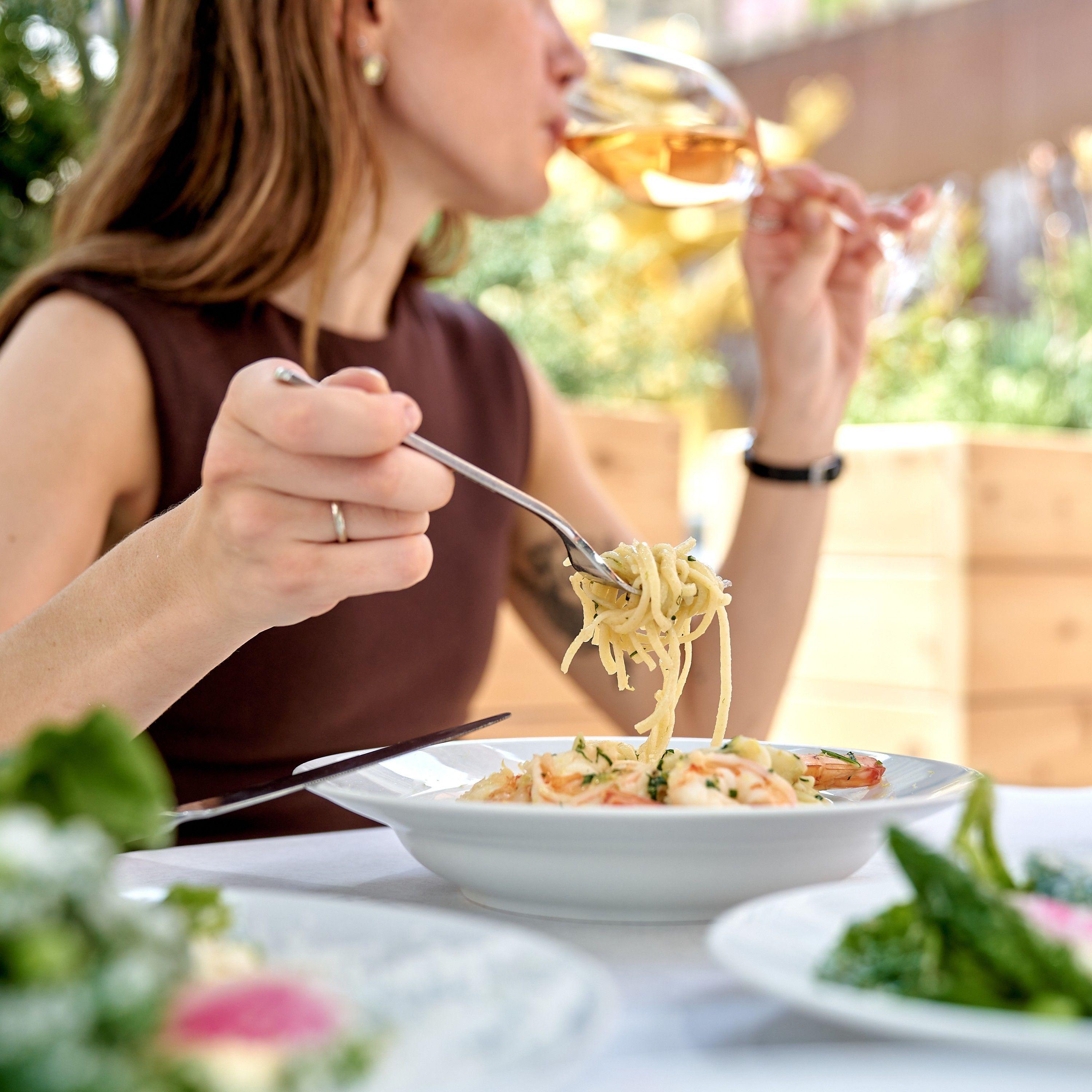 a woman drinking wine and eating pasta at jupiter