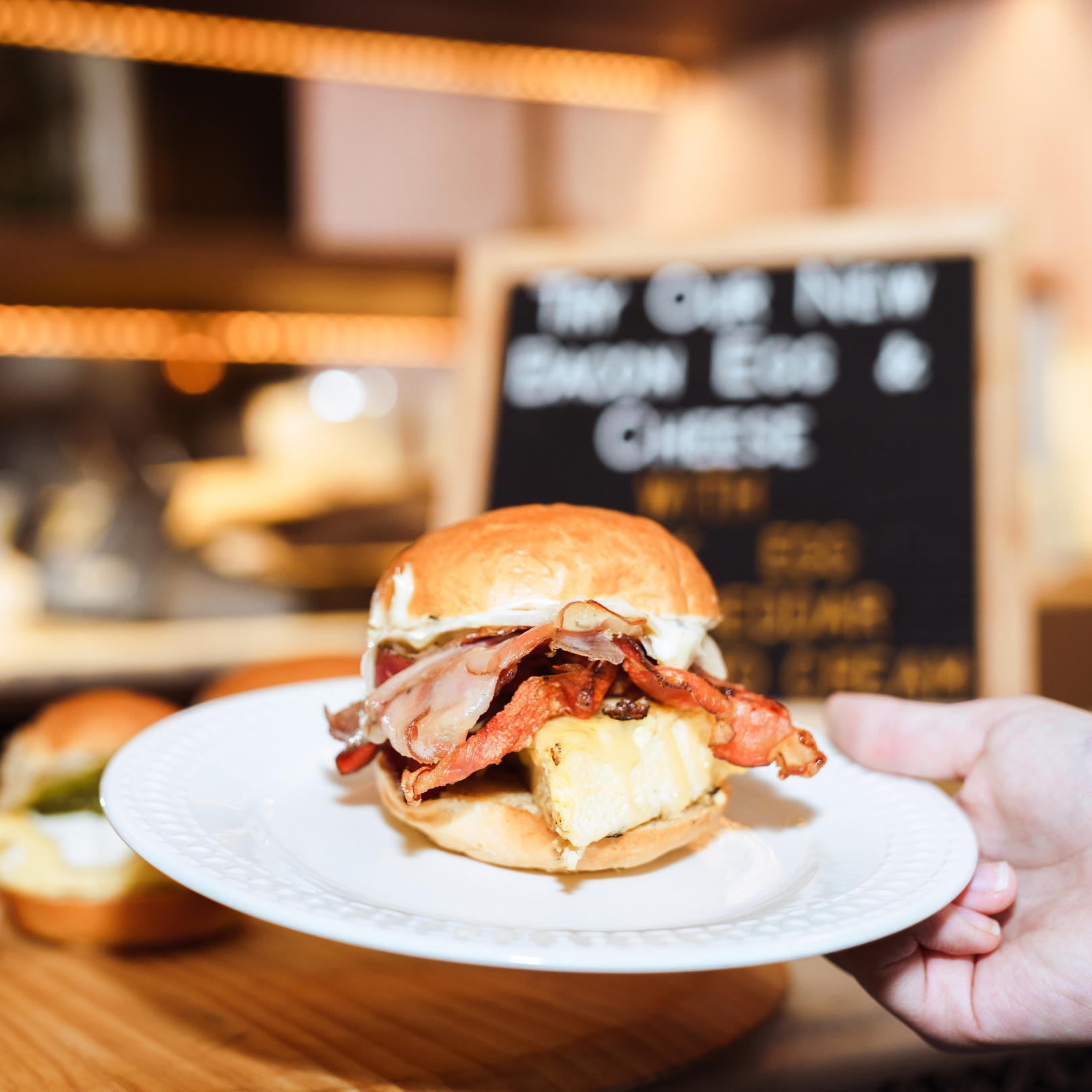Hand holding a plate with breakfast sandwich from Alidoro at Rockefeller Center