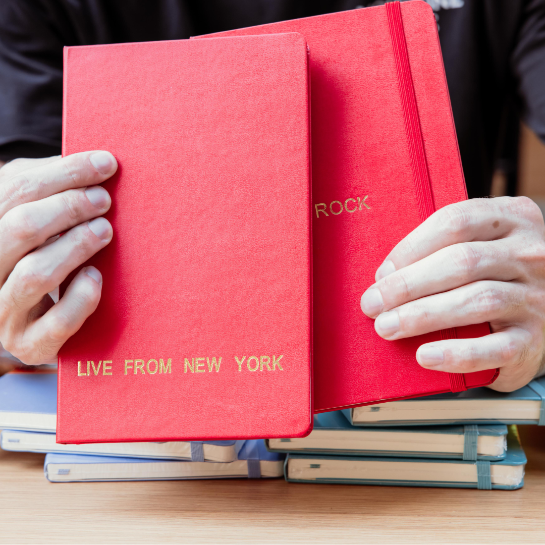 Two hands holding two red notebooks from Moleskine
