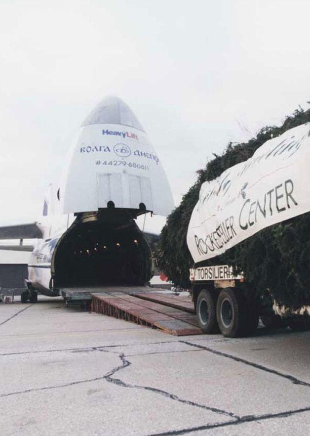 Color photo of the Rockefeller Center Christmas Tree being unloaded from a large cargo plane onto a truck in 1998.