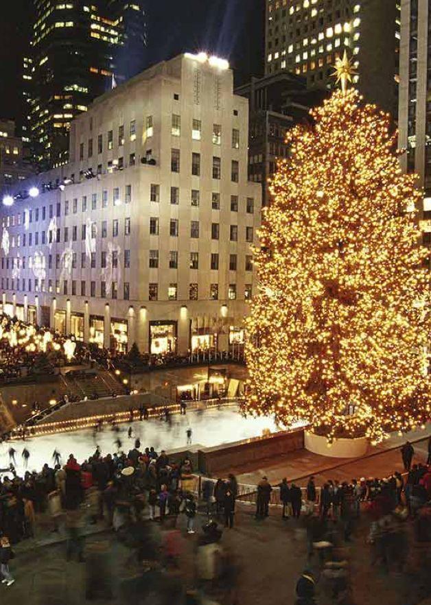 Color photo of the Rockefeller Center Christmas Tree fully lit in 1999, towering above the rink and surrounded by crowds.