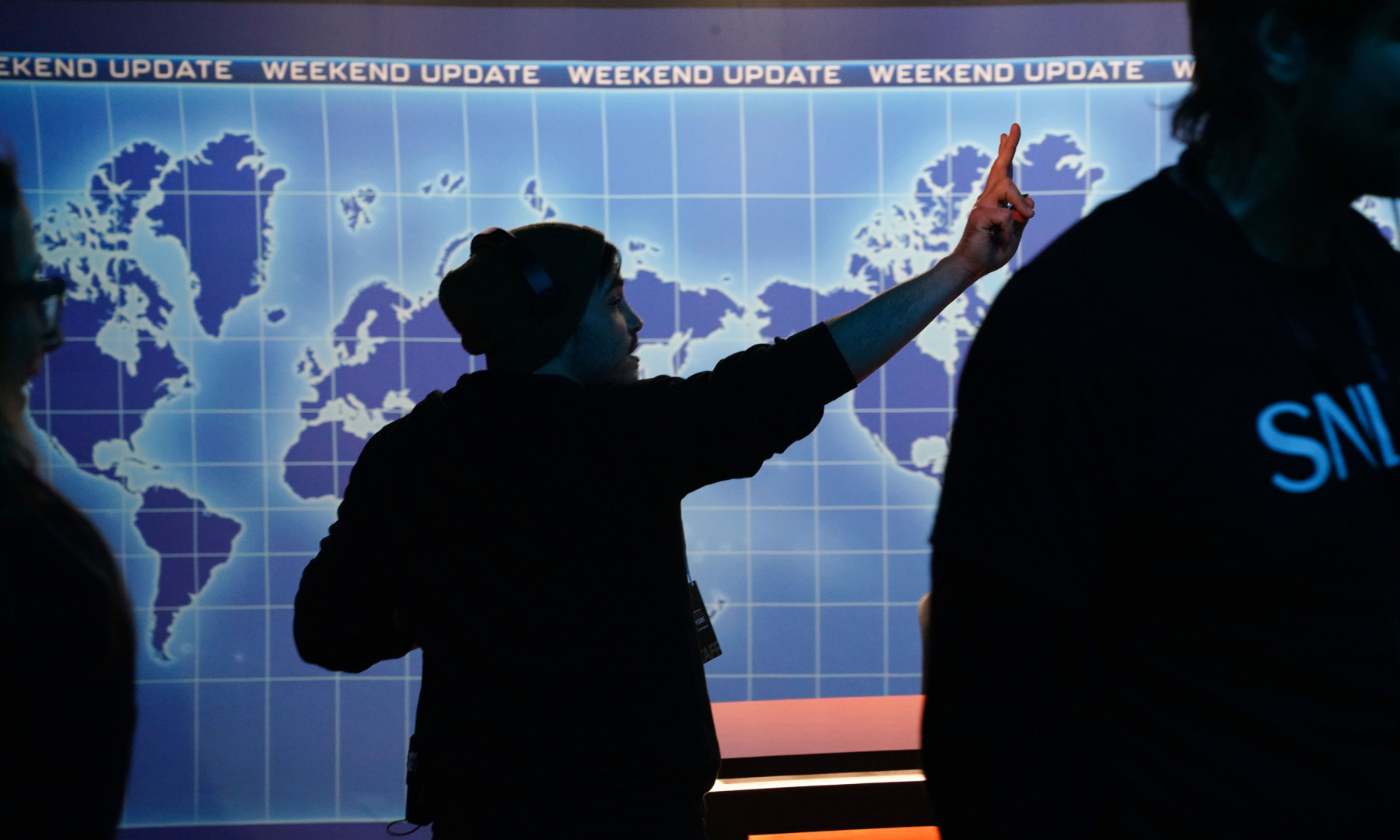 Person coordinating a recreation of Weekend Update at the SNL50 Anniversary Experience