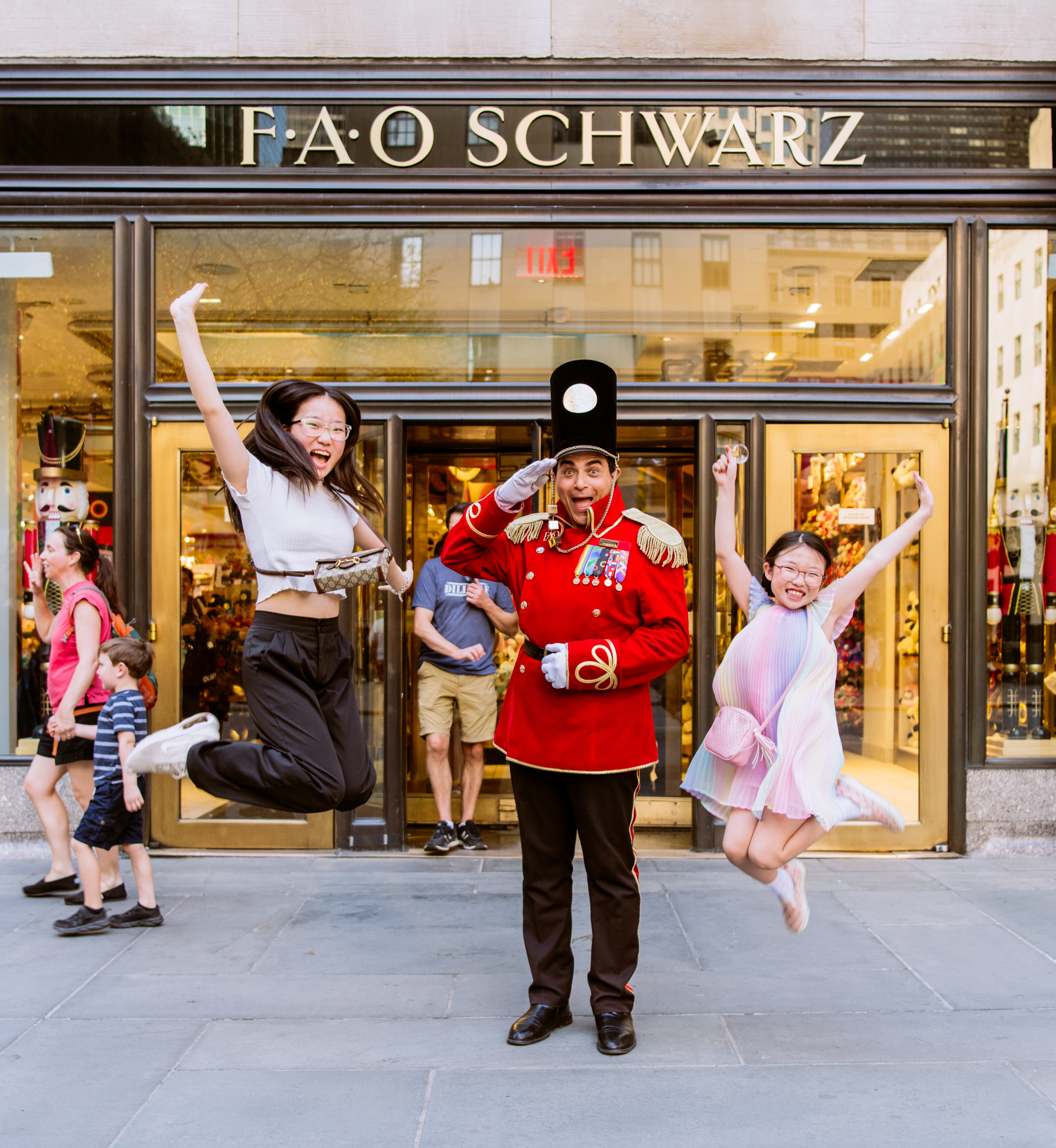 Two kids jumping in the air next to an FAO Schwarz toy soldier