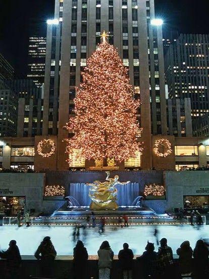 Nighttime photo of the Rockefeller Center Christmas Tree in 2001, illuminated above the rink with skaters and crowds gathered below.