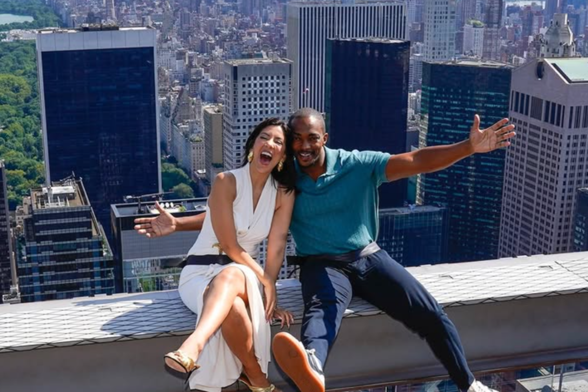 Anthony Mackie and Stephanie Beatriz on the beam at top of the rock