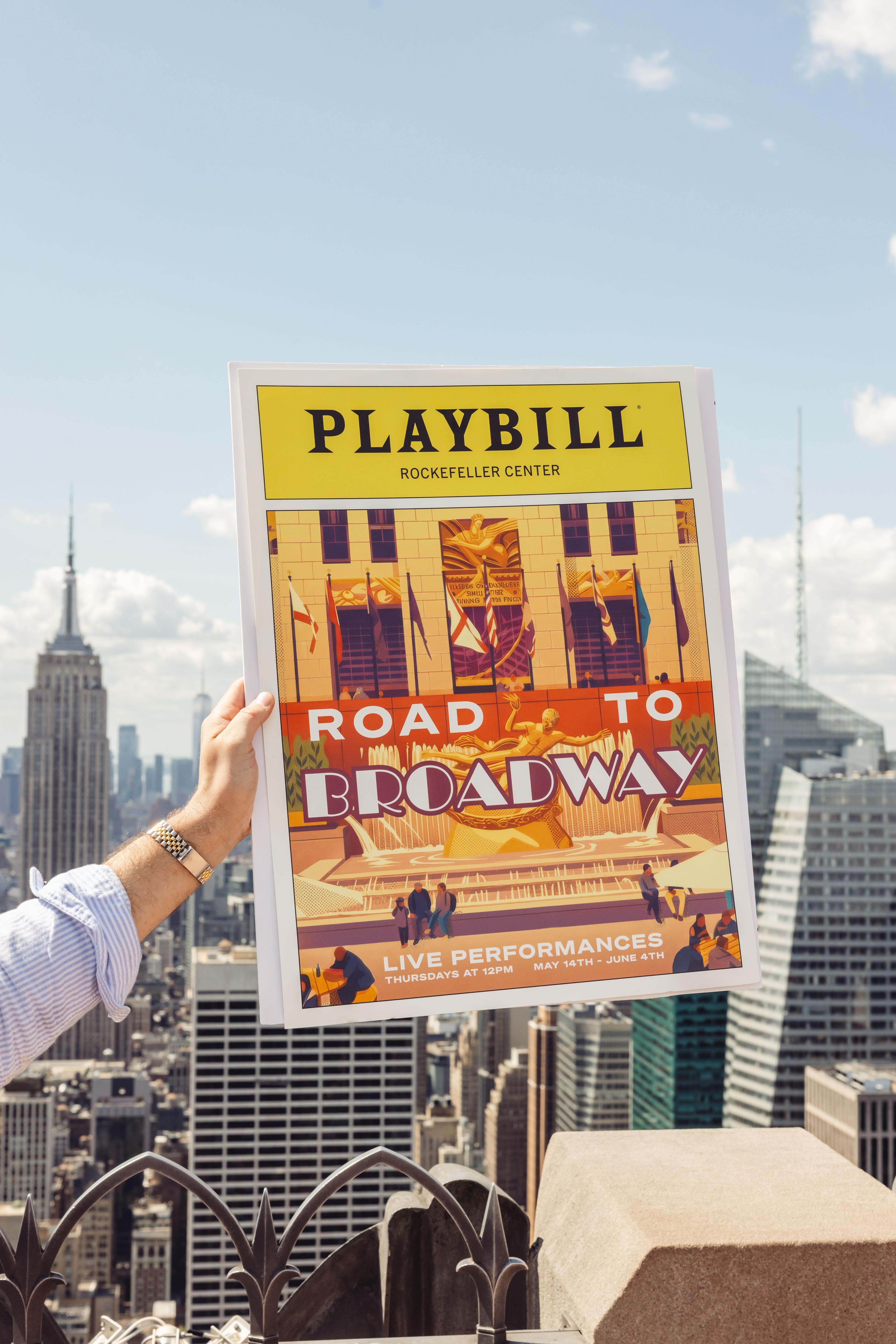 person holding Road to Broadway poster at Top of the Rock