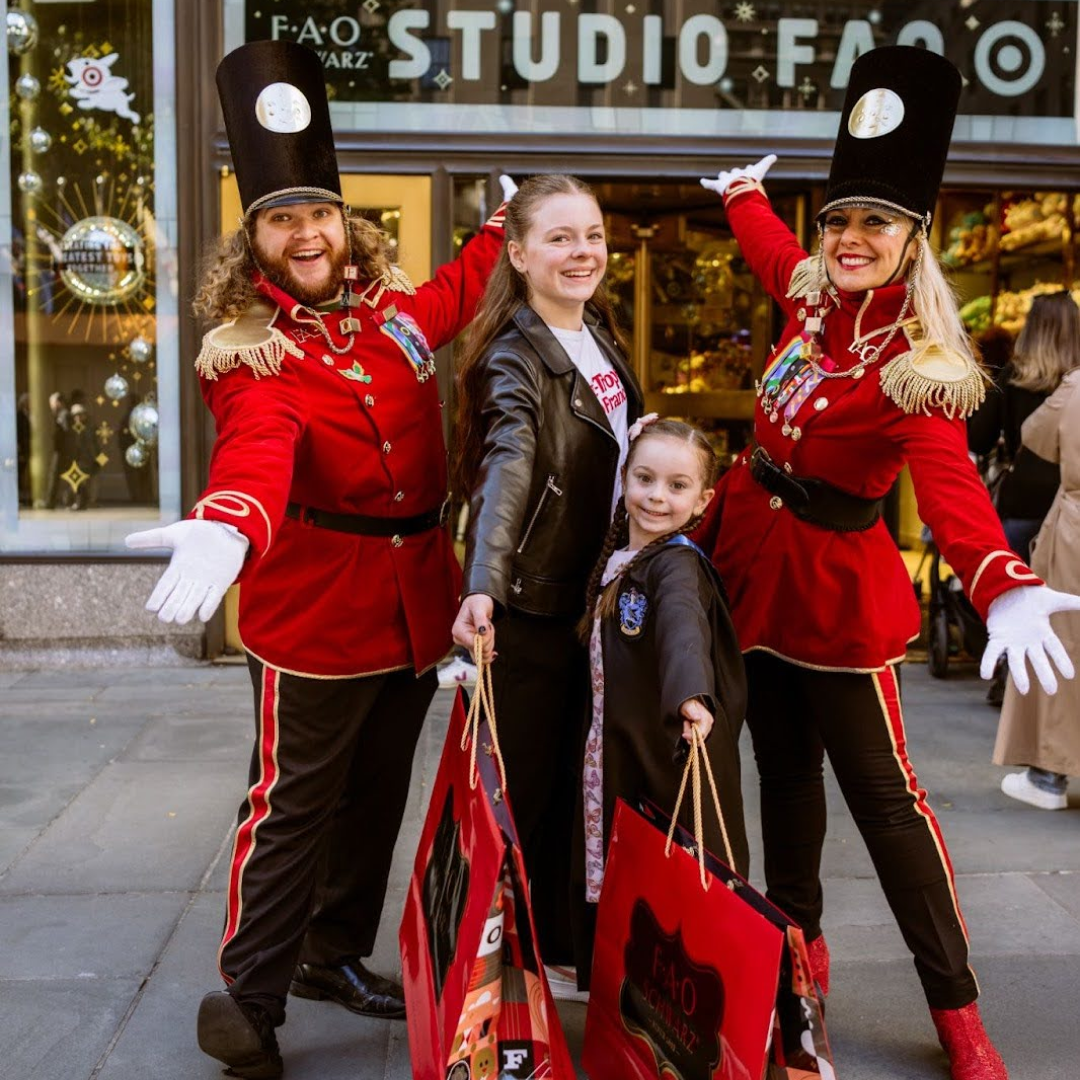 Two kids posing with two toy soldiers outside of FAO Schwarz at Rockefeller Center