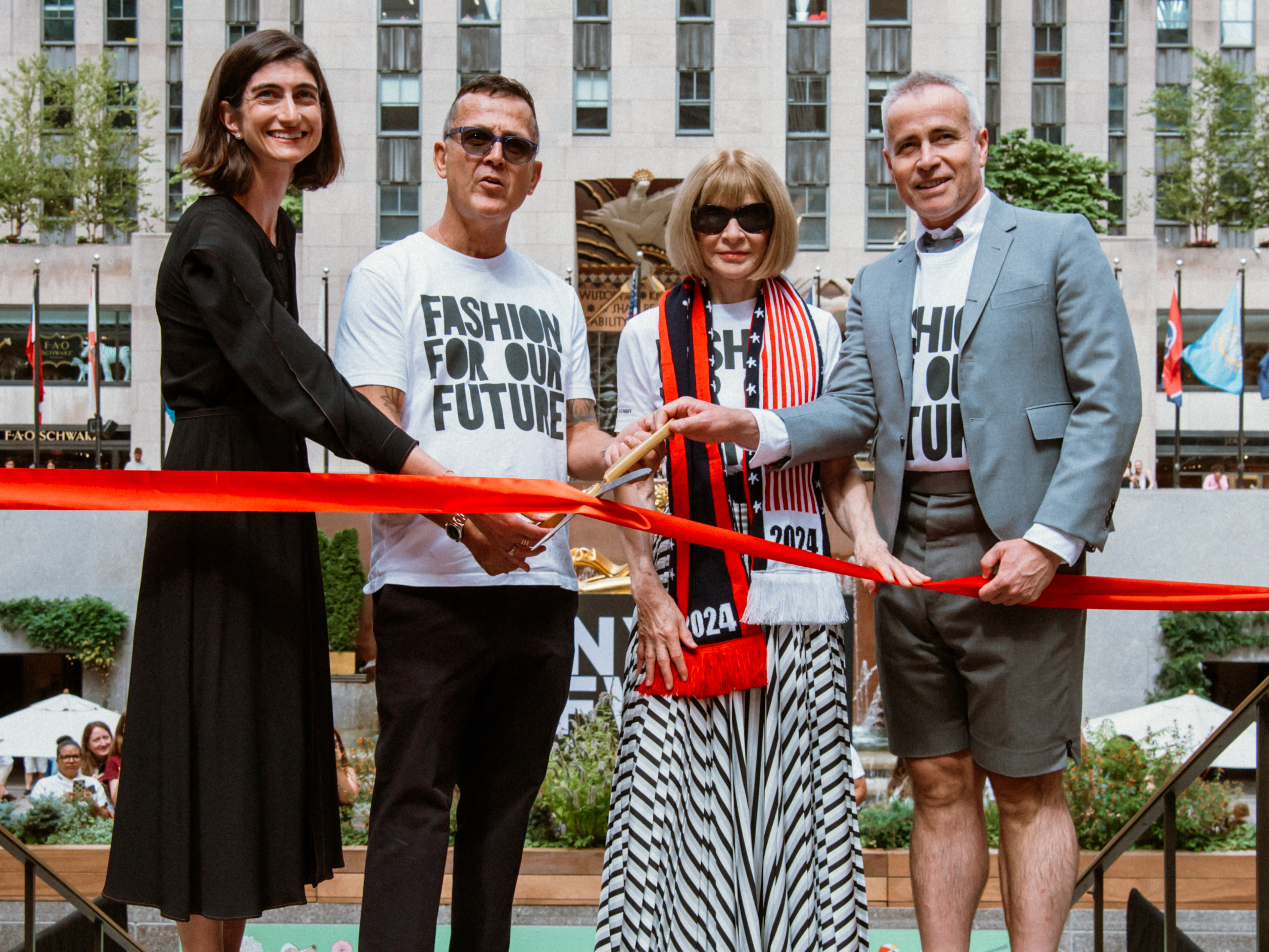 Four people cutting a red ribbon to mark the start of New York Fashion Week at Rockefeller Center